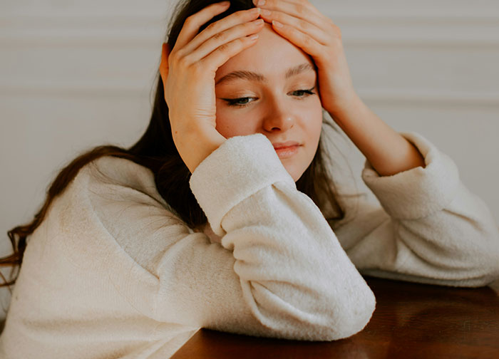 Young woman in a white sweater looking upset, reflecting on hurtful things doctors said that prompted changing doctors.