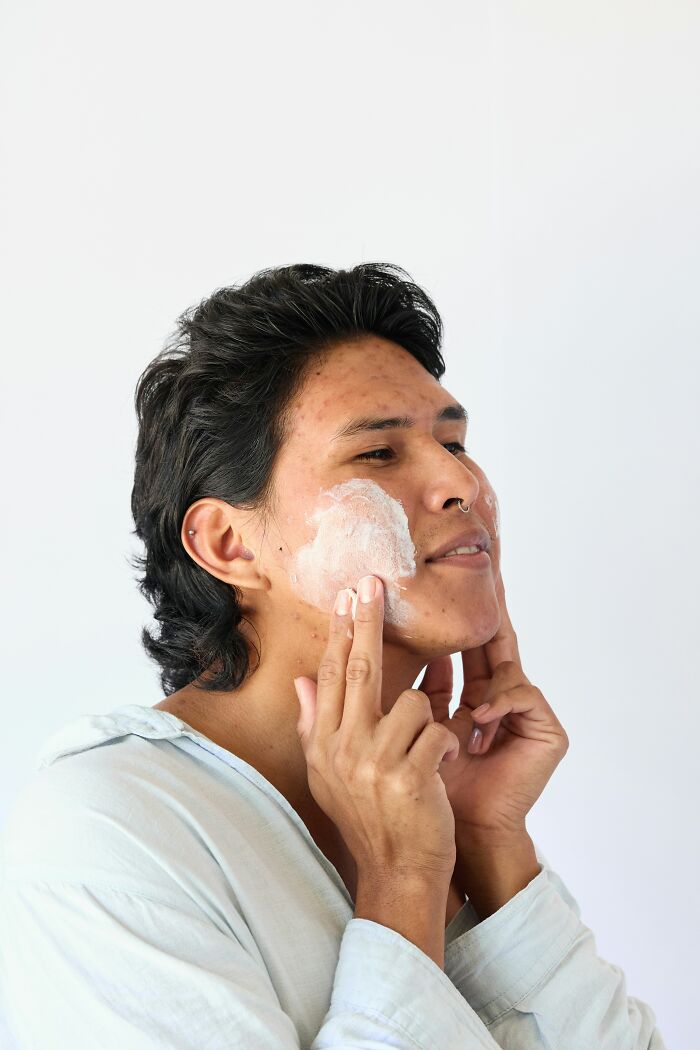 Young man applying skincare cream to face, highlighting common mundane things that make people sick and affect skin health.