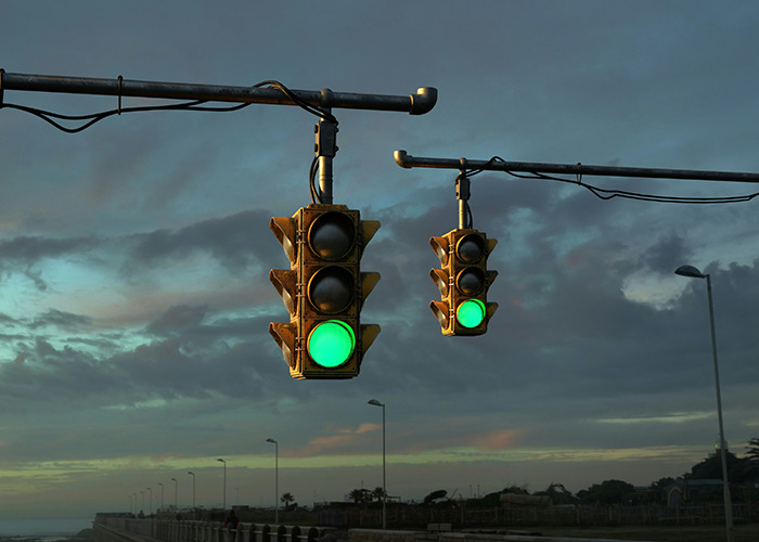 Green traffic lights hanging over an empty road at dusk under a cloudy sky symbolizing medical field employee decisions.