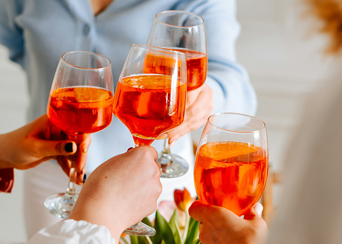 Medical field employees toasting with orange drinks during a casual gathering celebrating teamwork and dedication.