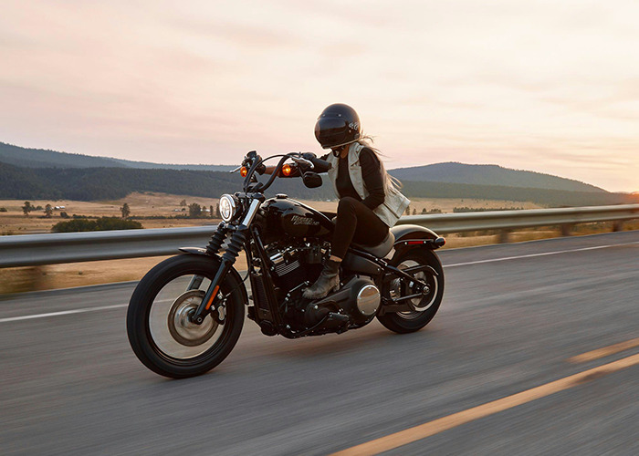 Woman riding a motorcycle on an open road with mountains in the background, symbolizing freedom from medical field employees.