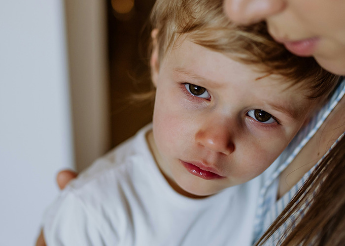 Young child in a white shirt being comforted by an adult, highlighting empathy in the medical field employees context.