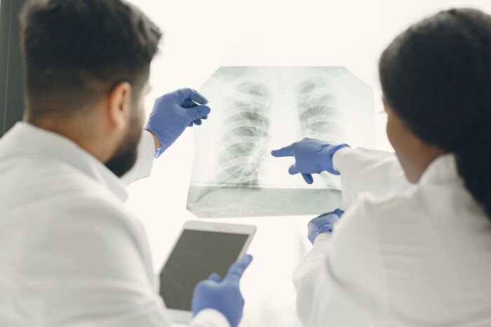 Two medical professionals examining a chest X-ray displaying unique body features and anatomical details.