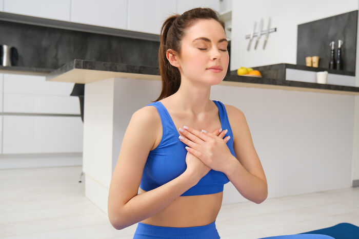 Young woman with unique body features practicing mindfulness and self-care indoors, wearing blue workout clothes.