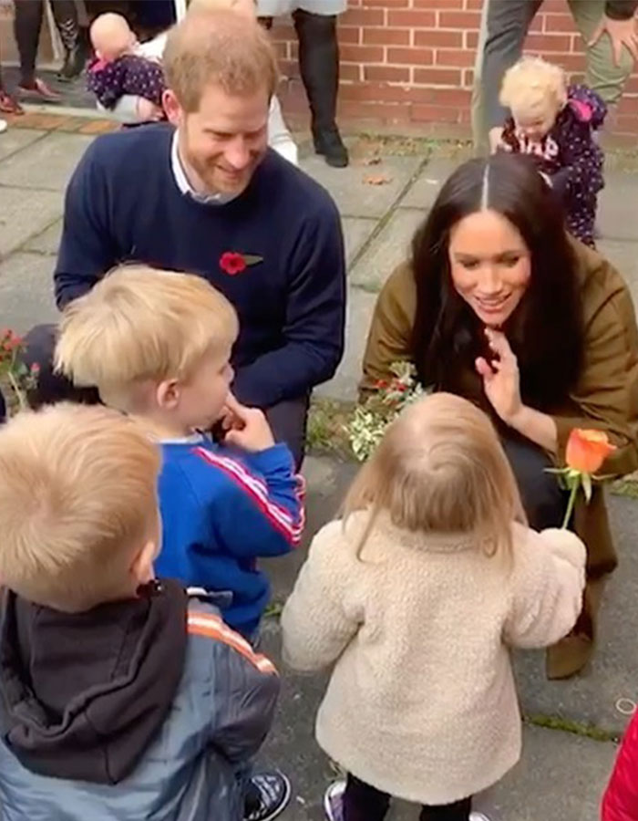 Prince Harry and Meghan interacting with children outdoors amid mental health concerns and family crisis discussions.
