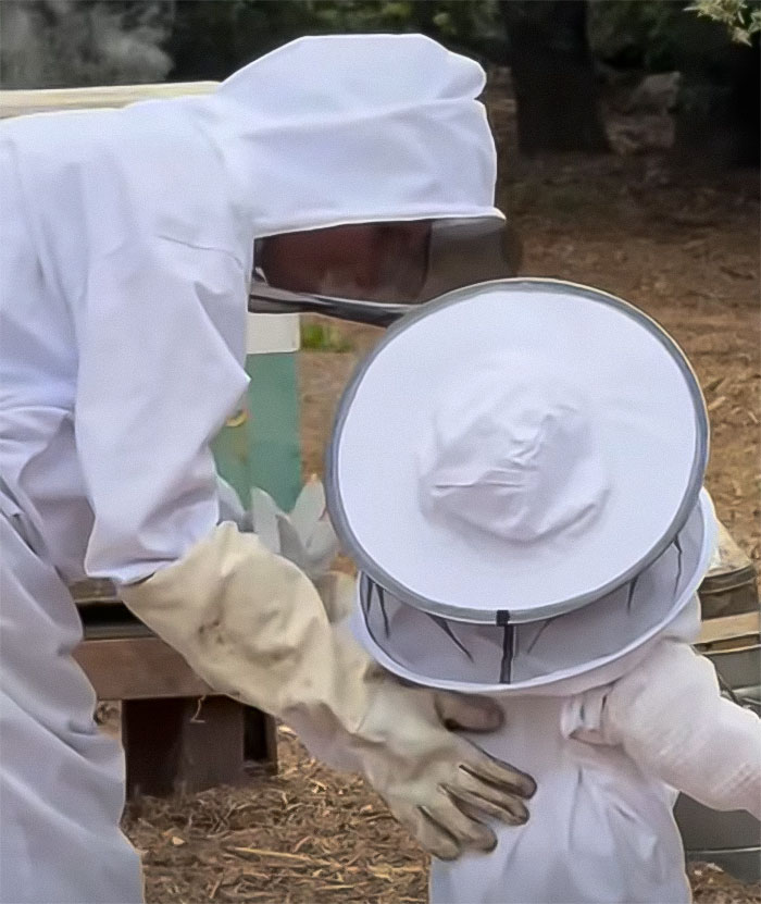 Meghan Markle and 3-year-old Lilibet dressed in beekeeping suits tending to a beehive outdoors in a garden. Meghan Markle and 3-year-old Lilibet dressed in beekeeping suits tending to a beehive outdoors in a garden.