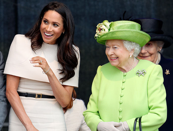 Meghan Markle smiling next to Queen Elizabeth in a bright outfit, related to wedding caterer controversy and royal intervention.