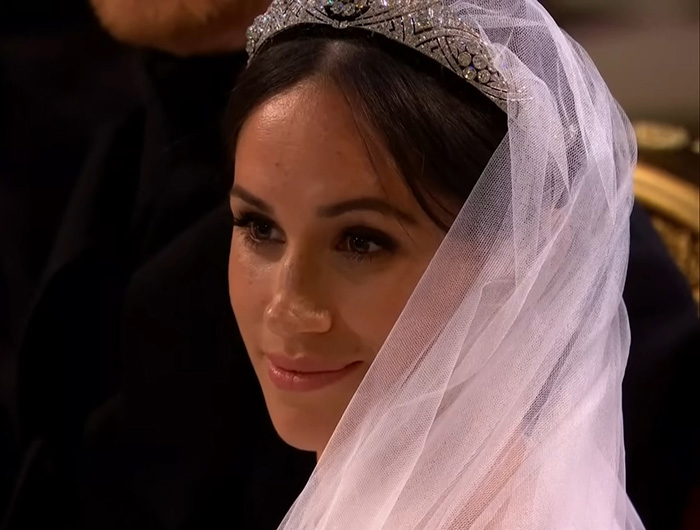 Meghan Markle wearing a tiara and veil at her royal wedding, with a calm and composed expression.