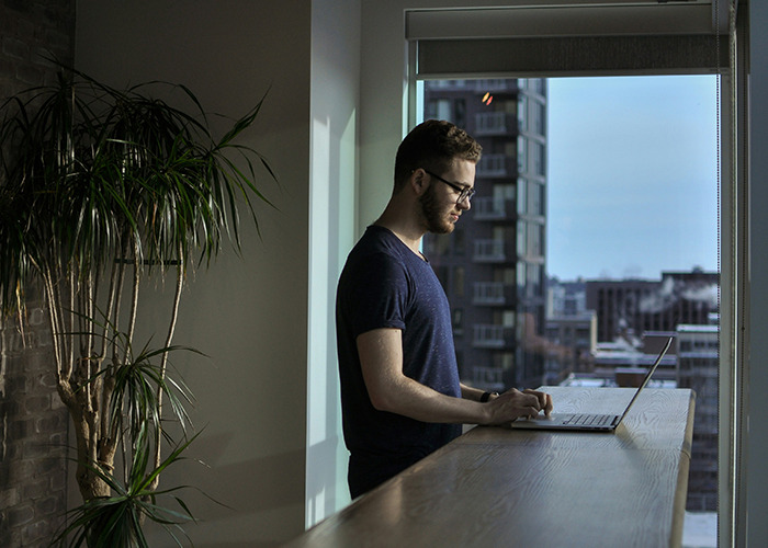 Man working on laptop near window in modern office, illustrating moments that would be outrageous if the genders were reversed.