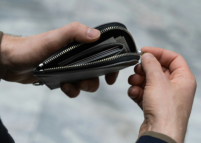Close-up of a man’s hands opening a black leather wallet, illustrating moments men share in everyday life.