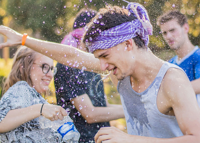Group of young men enjoying water fight outdoors, capturing moments that would be outrageous if the genders were reversed