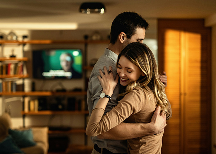 A man and woman sharing a warm hug indoors, capturing an intimate moment from men share outrageous moments perspectives.