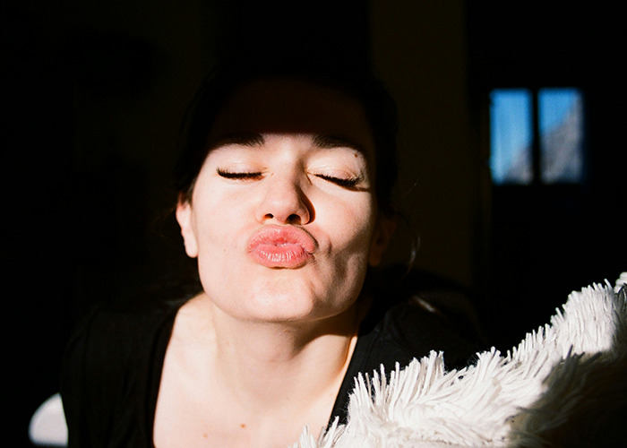 Close-up of a woman making a playful kiss face in sunlight, illustrating moments men share that would be outrageous reversed.
