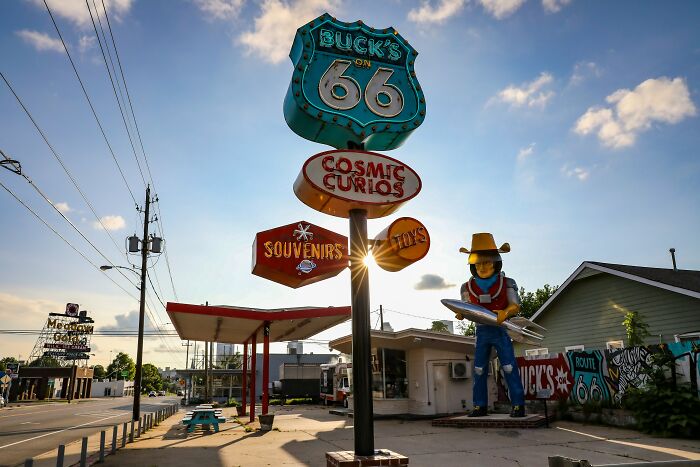 Vintage roadside Route 66 tourist destination featuring old signage and a cowboy statue at sunset, now a forgotten attraction.