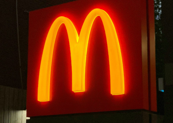 Neon McDonald's logo glowing at night, representing fast food related to mom refusing to leave kids with MIL.