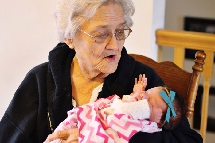 Elderly woman holding newborn baby wrapped in pink blanket, illustrating MIL steals baby and claims it’s a gift. Elderly woman holding newborn baby wrapped in pink blanket, illustrating MIL steals baby and claims it’s a gift.