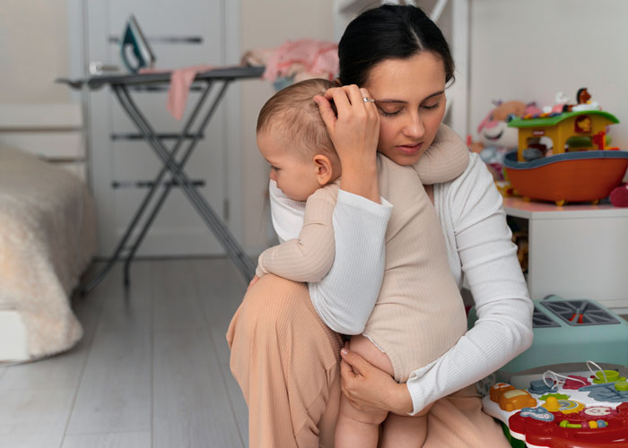Worried mother holding baby in a bedroom with toys nearby, reflecting on MIL stealing baby as a claimed gift for parents. Worried mother holding baby in a bedroom with toys nearby, reflecting on MIL stealing baby as a claimed gift for parents.
