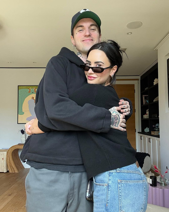 Couple embracing indoors with woman wearing sunglasses, related to Miley Cyrus fans calling out Demi Lovato over wedding dress.