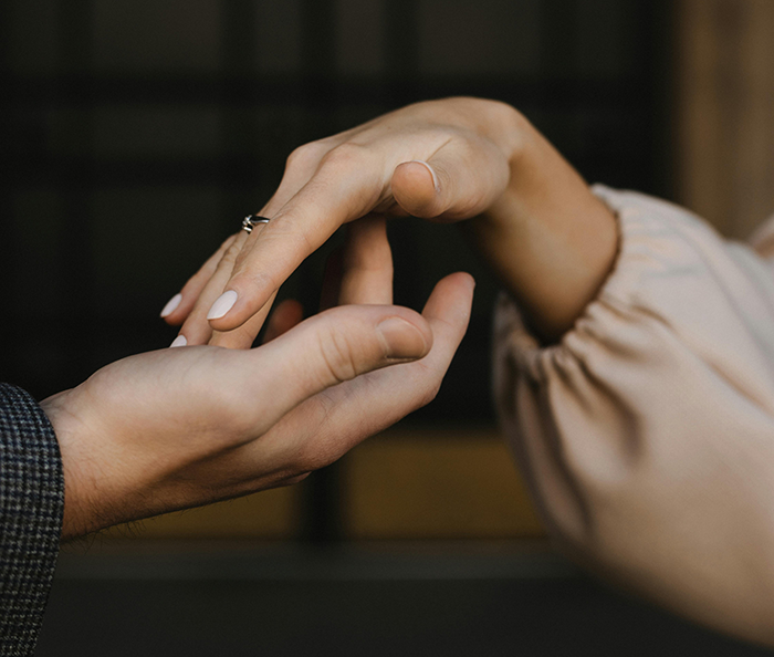 Close-up of couple holding hands, focusing on wedding ring, symbolizing wedding drama and loyalty test conflict.