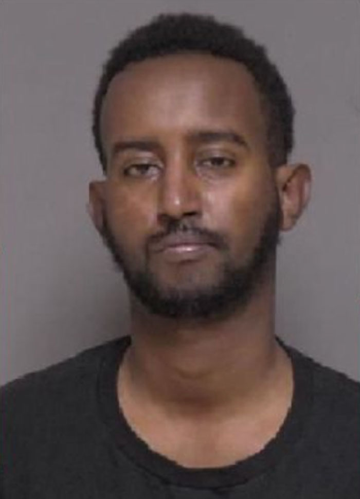 Mugshot of a man with a serious expression, related to a case involving a racist woman and playground incident.