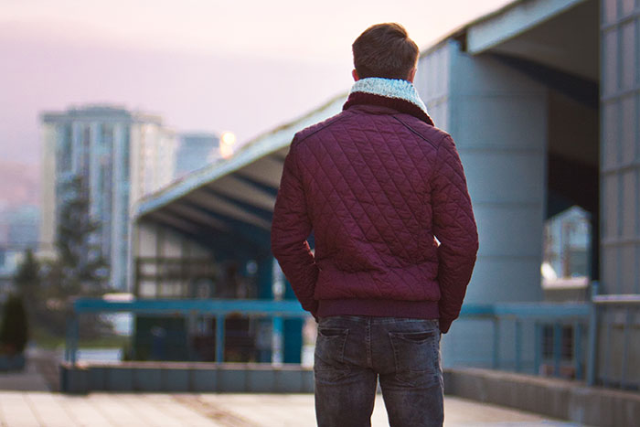 Man in a maroon jacket standing alone outdoors at dusk, reflecting real-life stories about instinct and late night safety.