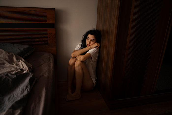 Young woman sitting on the floor hugging her knees, reflecting on real-life stories where instinct was everything.