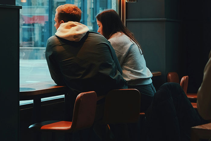 Two people sitting by a window in a dimly lit cafe, reflecting on real-life stories about instinct.