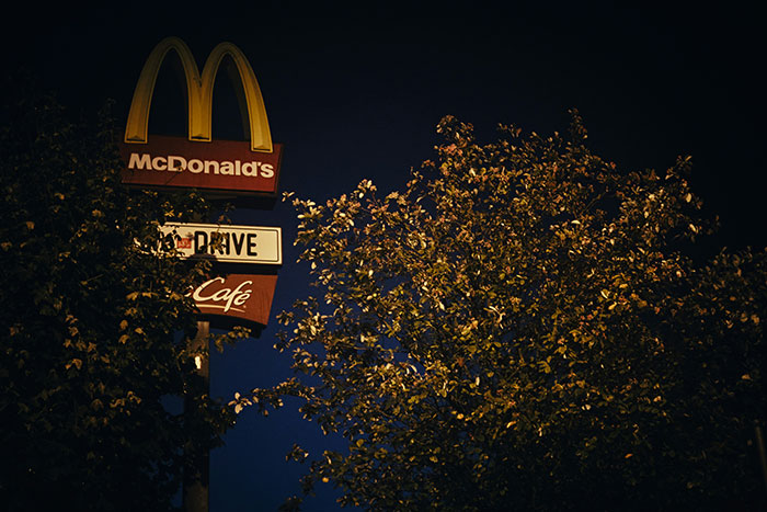 McDonald's illuminated sign at night near trees, reflecting the late night stroll instinct theme in real-life stories.