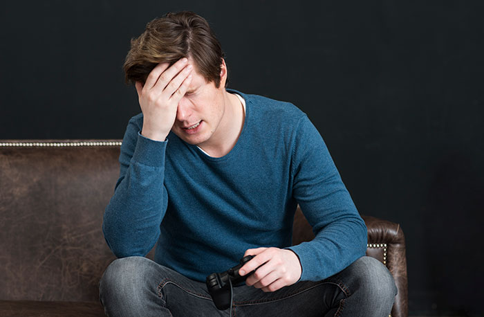 Young man looking stressed and holding a game controller, illustrating real-life stories where instinct was everything.