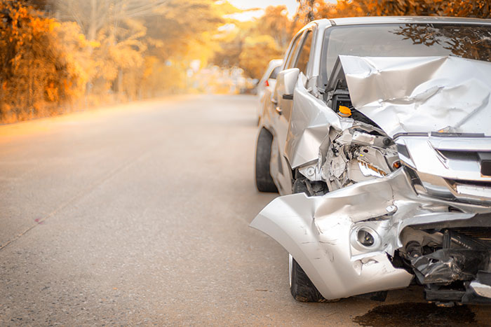 Damaged white car on roadside with front end crushed, illustrating real-life stories where instinct was everything.