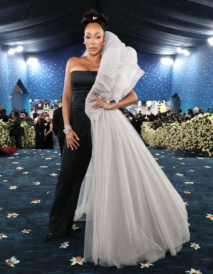 Woman in a two-tone black and white gown posing on the Met Gala 2025 red carpet with photographers in the background