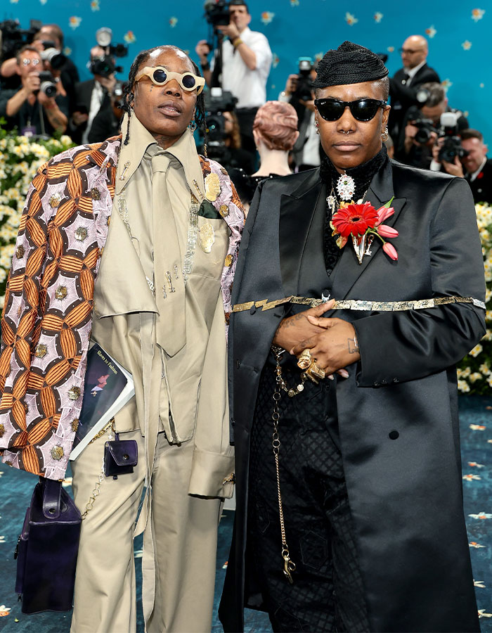 Two individuals dressed in bold outfits and sunglasses posing at Met Gala 2025 red carpet event.