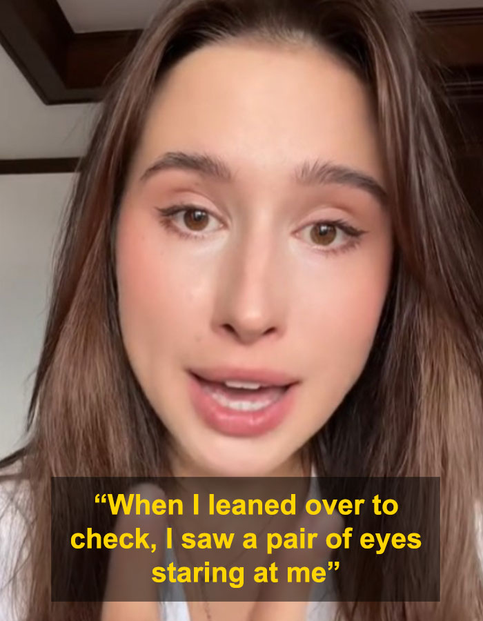 Woman recounting solo traveler spotting stranger hiding under hotel bed during phrogging incident in attic.