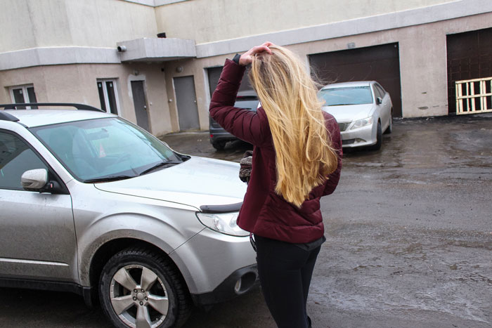 Woman with long blonde hair standing by a silver car in a parking lot, showing entitled behavior in neighbor's spot conflict. Woman with long blonde hair standing by a silver car in a parking lot, showing entitled behavior in neighbor's spot conflict.