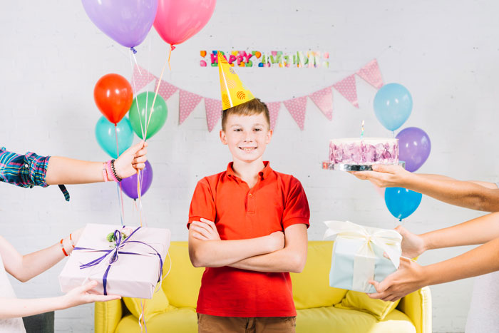 Young boy celebrating birthday party with balloons and gifts, highlighting nephew excluded from son's birthday controversy.
