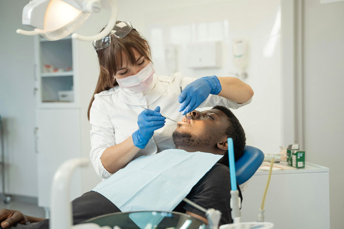 Dentist examining patient&rsquo;s teeth in clinic, highlighting issues related to man telling girlfriend his teeth aren&rsquo;t real after years.