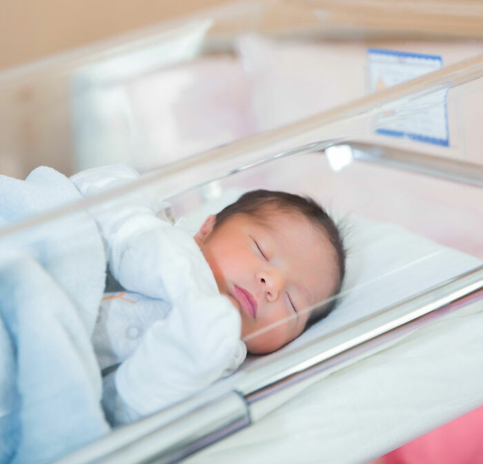 Newborn baby peacefully sleeping in a hospital bassinet, representing hilariously bad names that make people question parenting choices.
