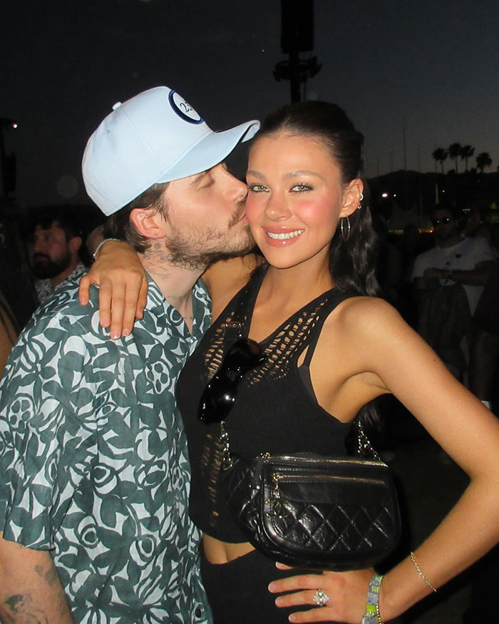 Nicola Peltz smiling while man kisses her cheek outdoors at night, related to David Beckham narcissistic family feud news.