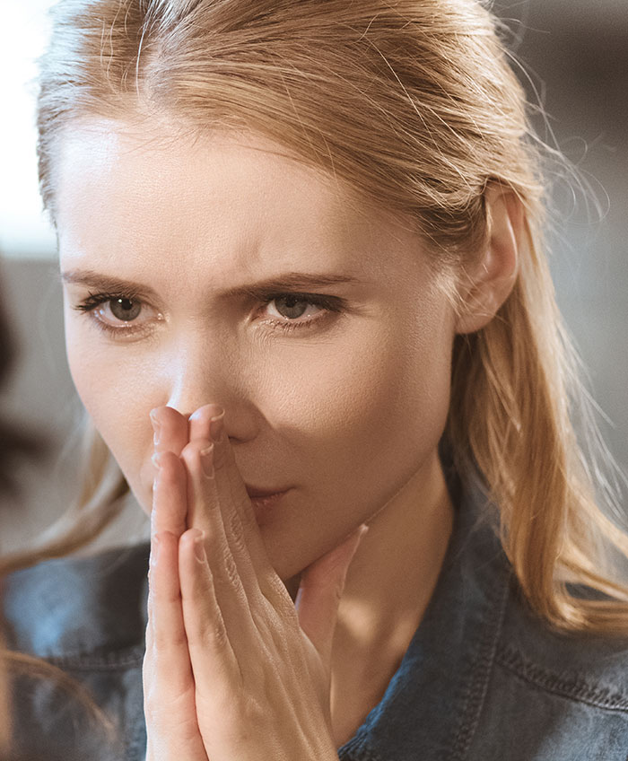 Woman with a worried expression, reflecting on alopecia and cultural headscarf controversy in a tense moment.