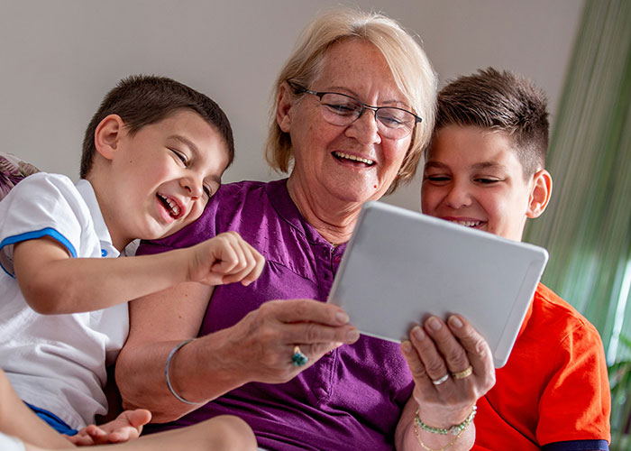 Grandmother spending time with kids using a tablet, highlighting concerns about kids being fed fast food by MIL.