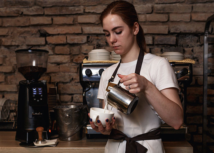 Barista pouring coffee with focus inside a rustic cafe, demonstrating decaf revenge and respect lesson.