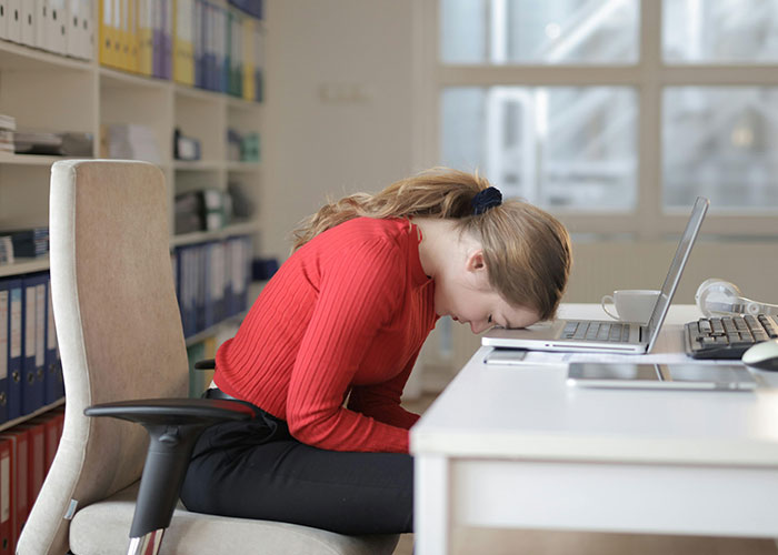 Barista uses decaf revenge with a laptop on the desk, showing frustration in a bright office setting.