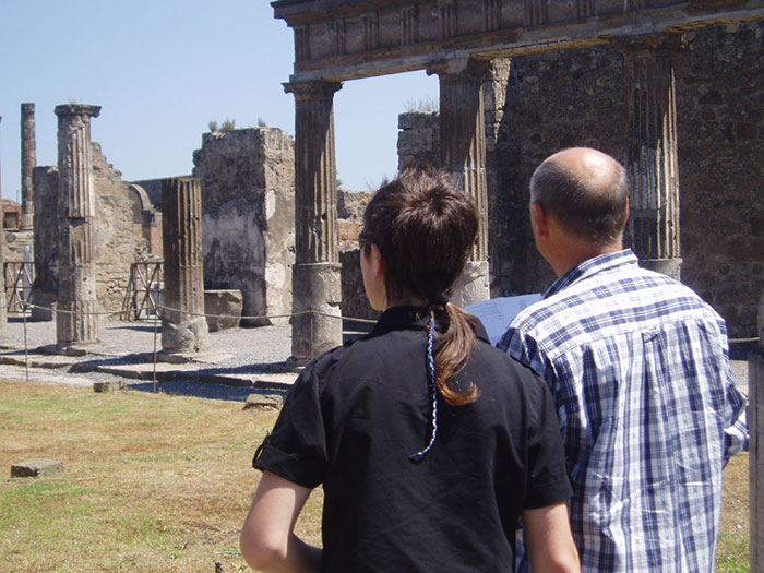Two people exploring ancient ruins outdoors, reflecting on past fashion trends like stirrup pants.