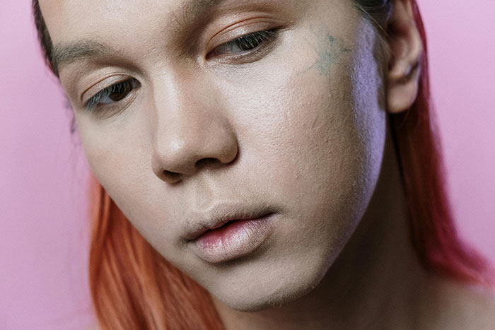Close-up of a young person with red hair and minimal makeup reflecting on fashion trends like stirrup pants from their youth.