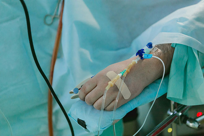 Close-up of a patient&rsquo;s hand with an IV drip in a medical setting, highlighting care in an apartment environment.