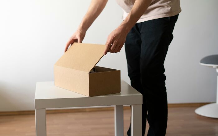 Person packing belongings in a box on a table symbolizing sharing company secrets after leaving a job.