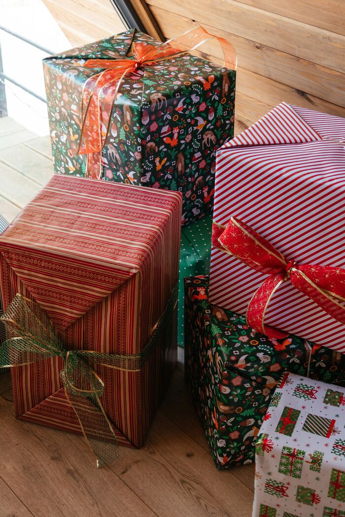 Colorful wrapped holiday gifts stacked near a wooden wall, evoking surprise moments shared in online shaming posts.