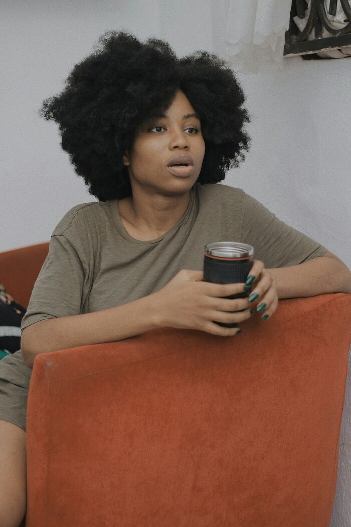 Woman with natural hair holding a cup, looking shocked and recalling outrageously out-of-touch statements.