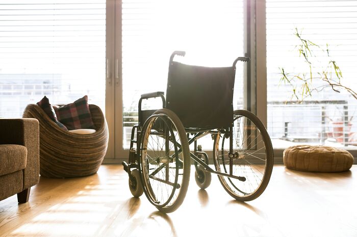 Wheelchair in sunlit modern living room with cozy chair and cushions, illustrating moments people got shamed online.
