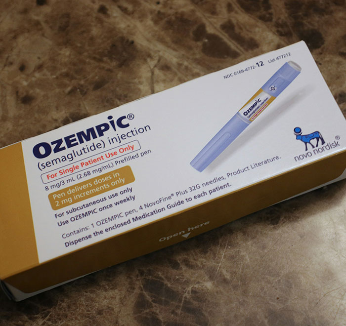 Ozempic injection pen box on a marble surface, highlighting ozempic tongue as a weight-loss med side effect.